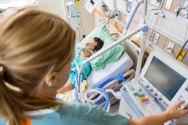 intensivvårdssjuksköterska som kontrollerar monitorn hos en man i sjukhussängen