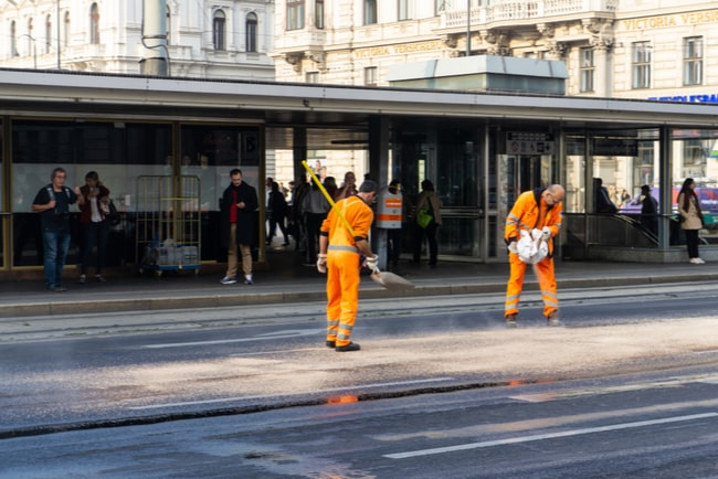 två män i orangea kläder som jobbar med spårvagnsrälsen