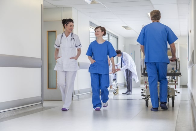 sjuksköterskor och läkare går genom sjukhuskorridor