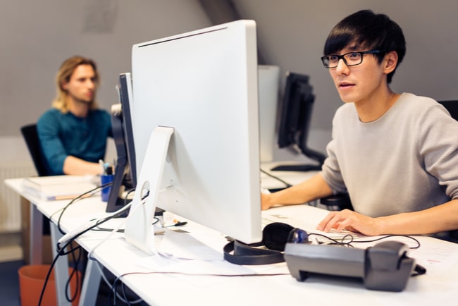 två unga män jobbar vid datorer