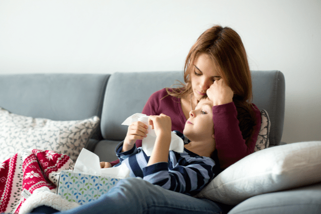 kvinna håller om sin sjuke son i soffa